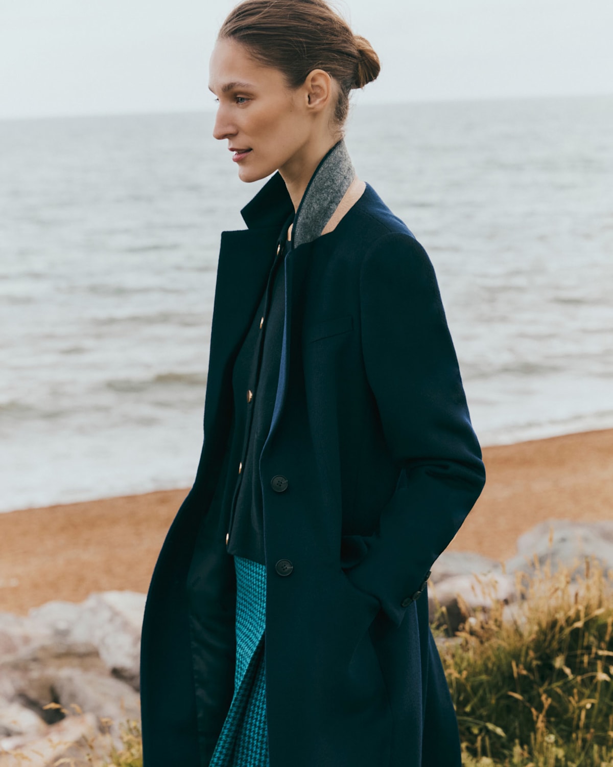 A model walking outside along the coast wearing a winter coat.